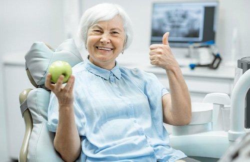 Patient holding an apple and giving a thumb’s up
