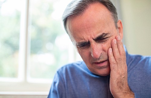 a man holding his jaw due to a dental emergency