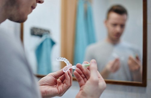 Male performing at-home teeth whitening in the bathroom