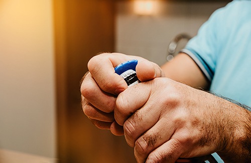 Closeup of patient using blue bottle cap opener