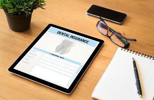 Tablet with dental insurance on it and glasses nearby