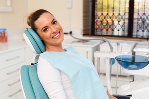 Female dental patient sitting in dental chair and smiling