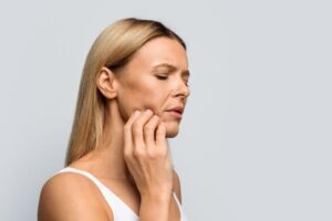 Woman grimacing due to jaw pain on one side 