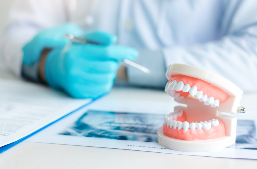 Dentures on desk with dentist's hand in background